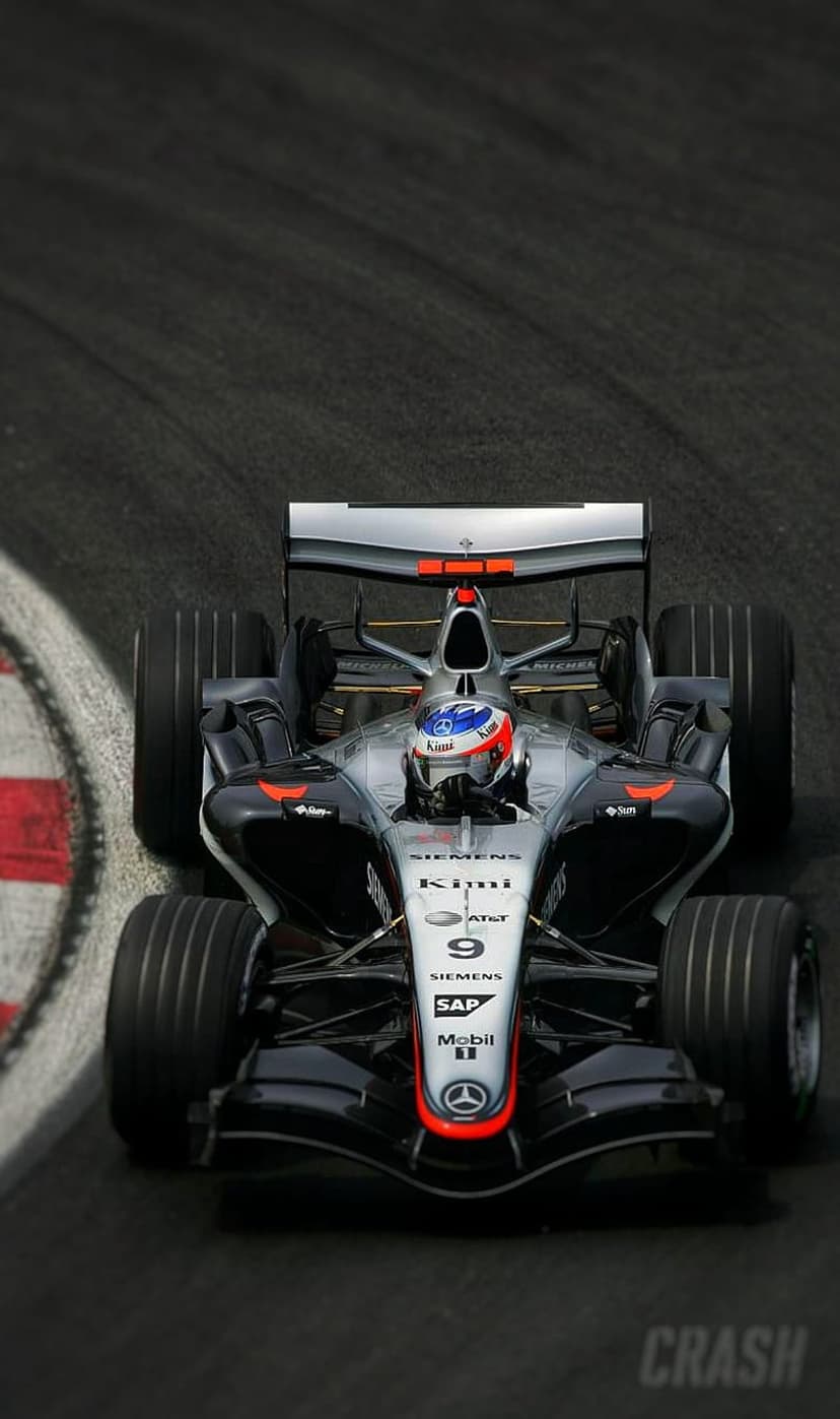 Kimi Raikkonen drives a silver McLaren MP4-20 F1 car around a race track curve with red and white kerbs.