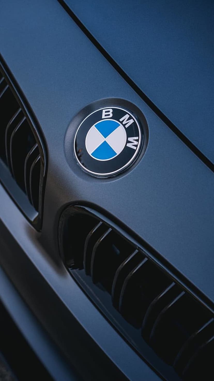 BMW logo on a navy blue mesh grille with polished silver edges and textured honeycomb patterns in close-up.