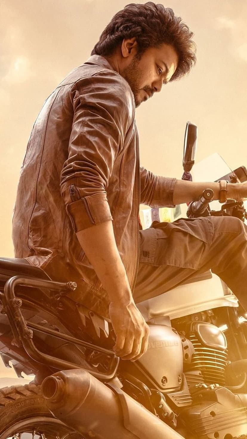 Man in a brown leather jacket sits on a motorcycle during sunset with warm lighting and a rugged aesthetic.