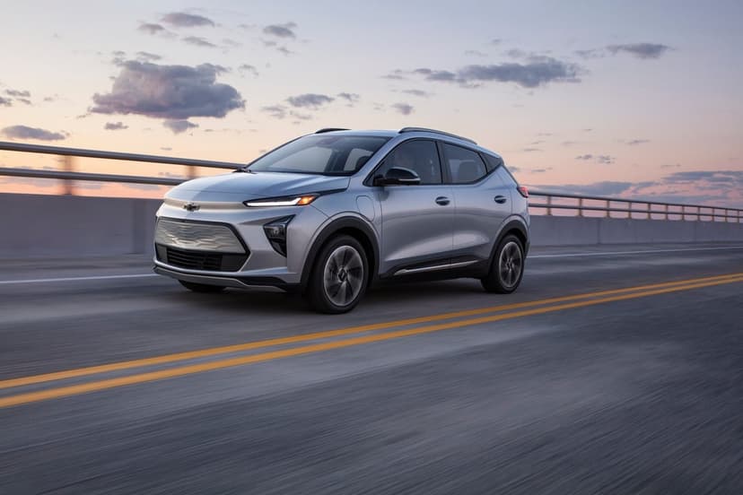 Silver Chevrolet Bolt EUV driving on a bridge at sunset with a colorful sky and motion blur on the road.