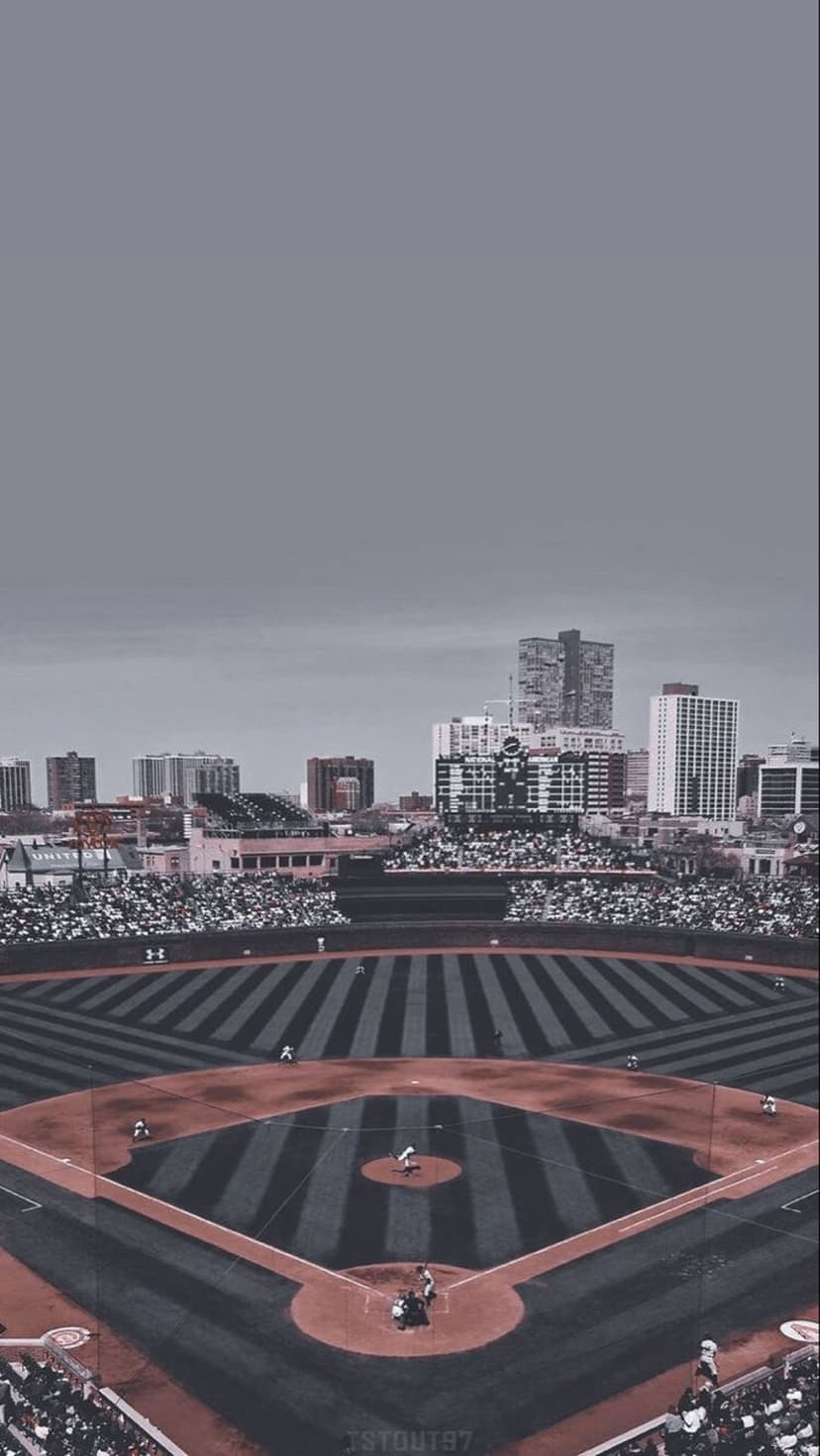 Professional baseball ballpark field and grandstands set against a metropolitan skyline in a vertical view.