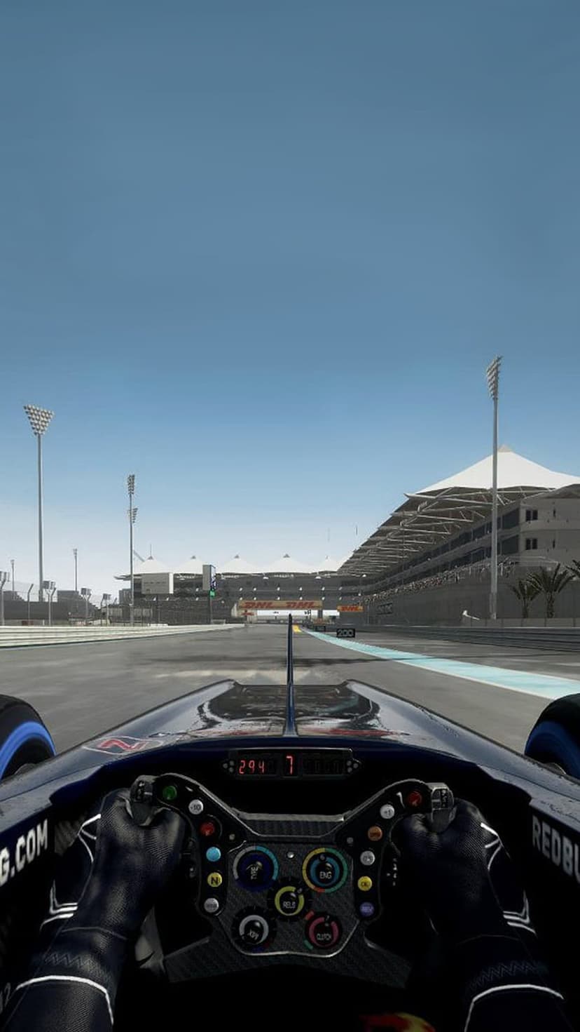 F1 car cockpit with a digital steering wheel facing the Yas Marina Circuit track under a bright blue sky.