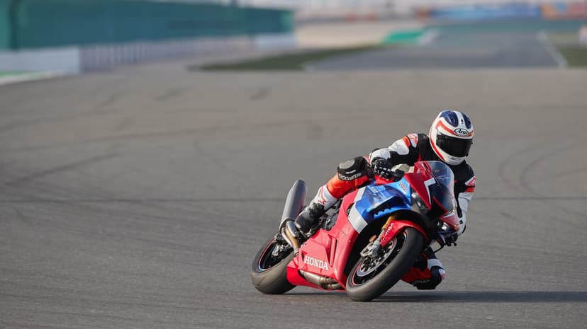Motorcyclist on a Honda sportbike leaning into a racetrack turn with a blurred background at sunset.