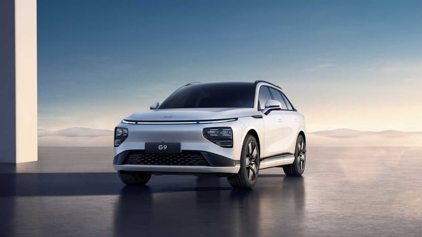 White XPeng G9 electric SUV parked on a reflective floor against a misty mountain background at dawn.