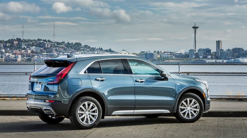 Blue Cadillac SUV parked on a concrete pier with the Seattle Space Needle and city skyline in the background.