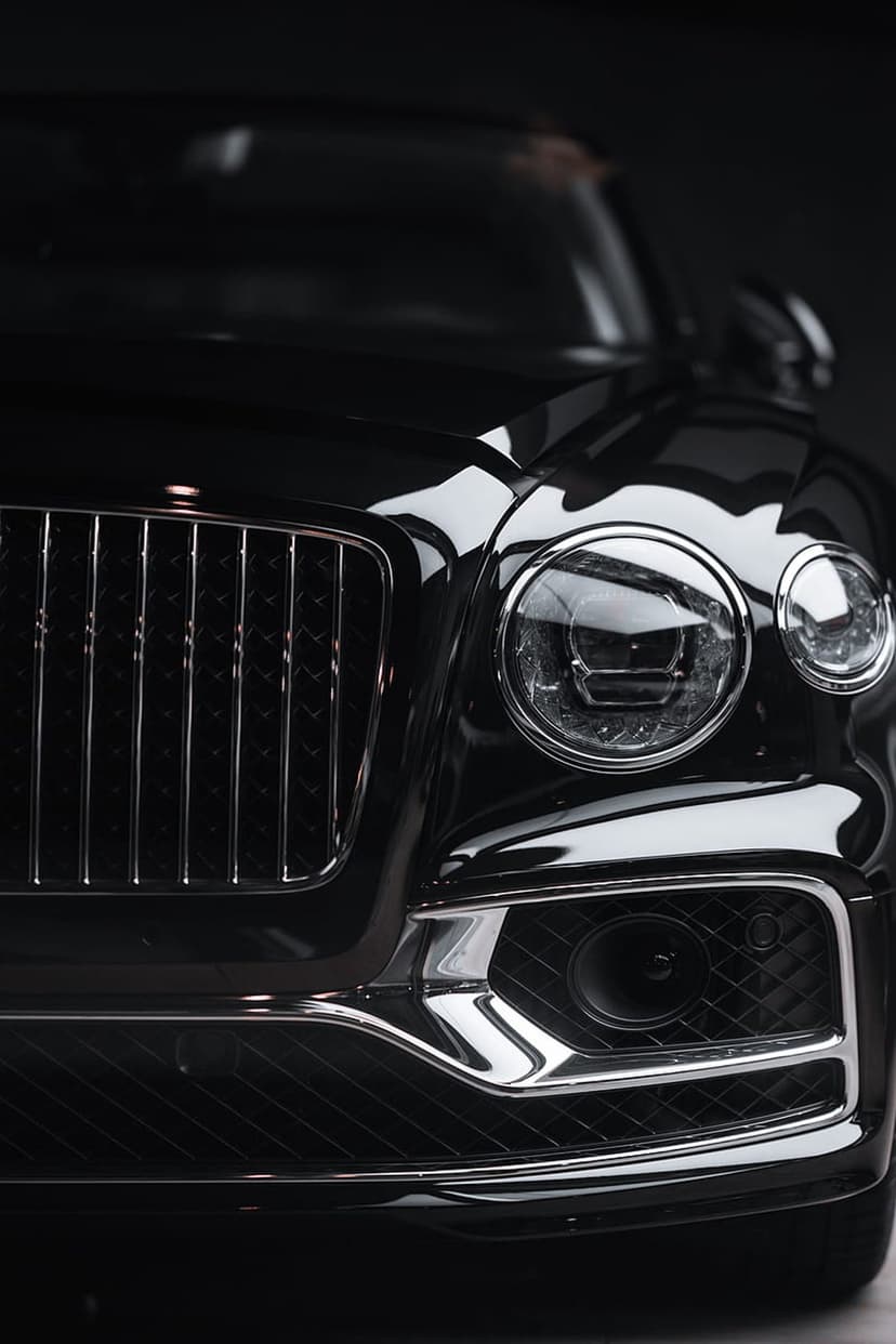 Black Bentley Continental GT front view featuring a chrome lattice grille and round LED headlights in close-up.
