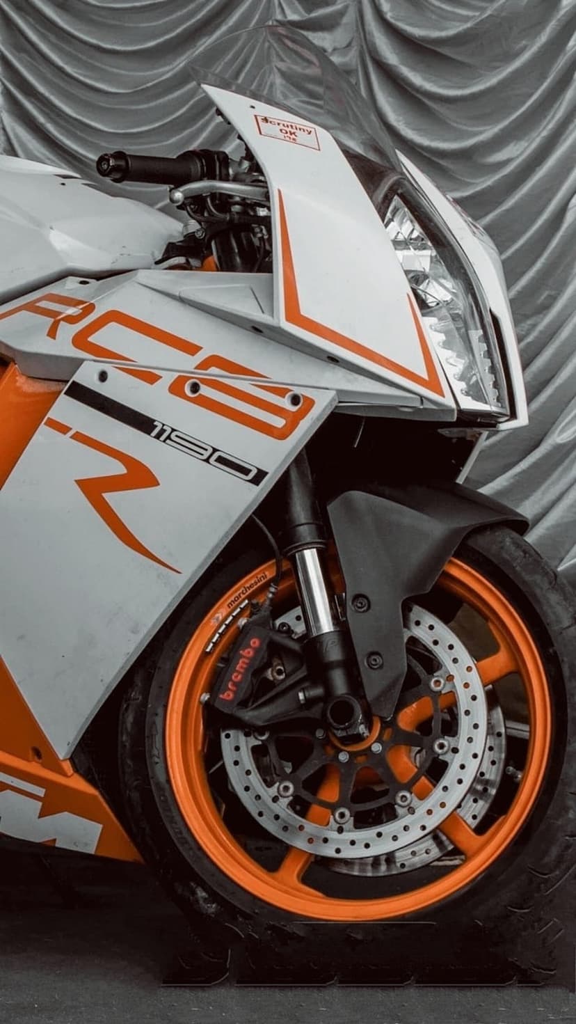 KTM RC 125 motorcycle with orange wheels and white fairings shown in a close-up front view with Brembo brakes.