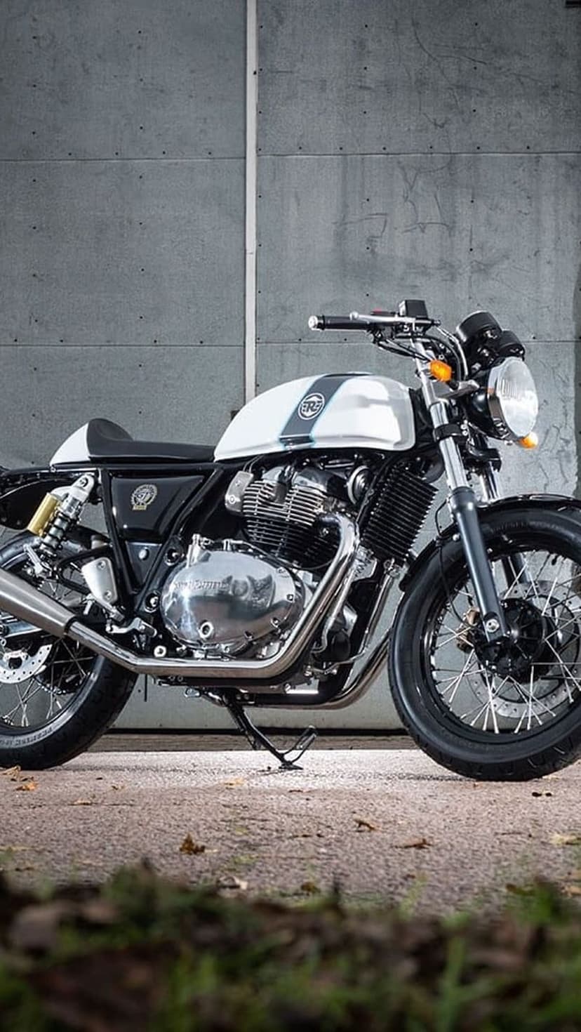 Royal Enfield Interceptor 650 motorcycle with a white tank and chrome engine against a textured gray stone wall.