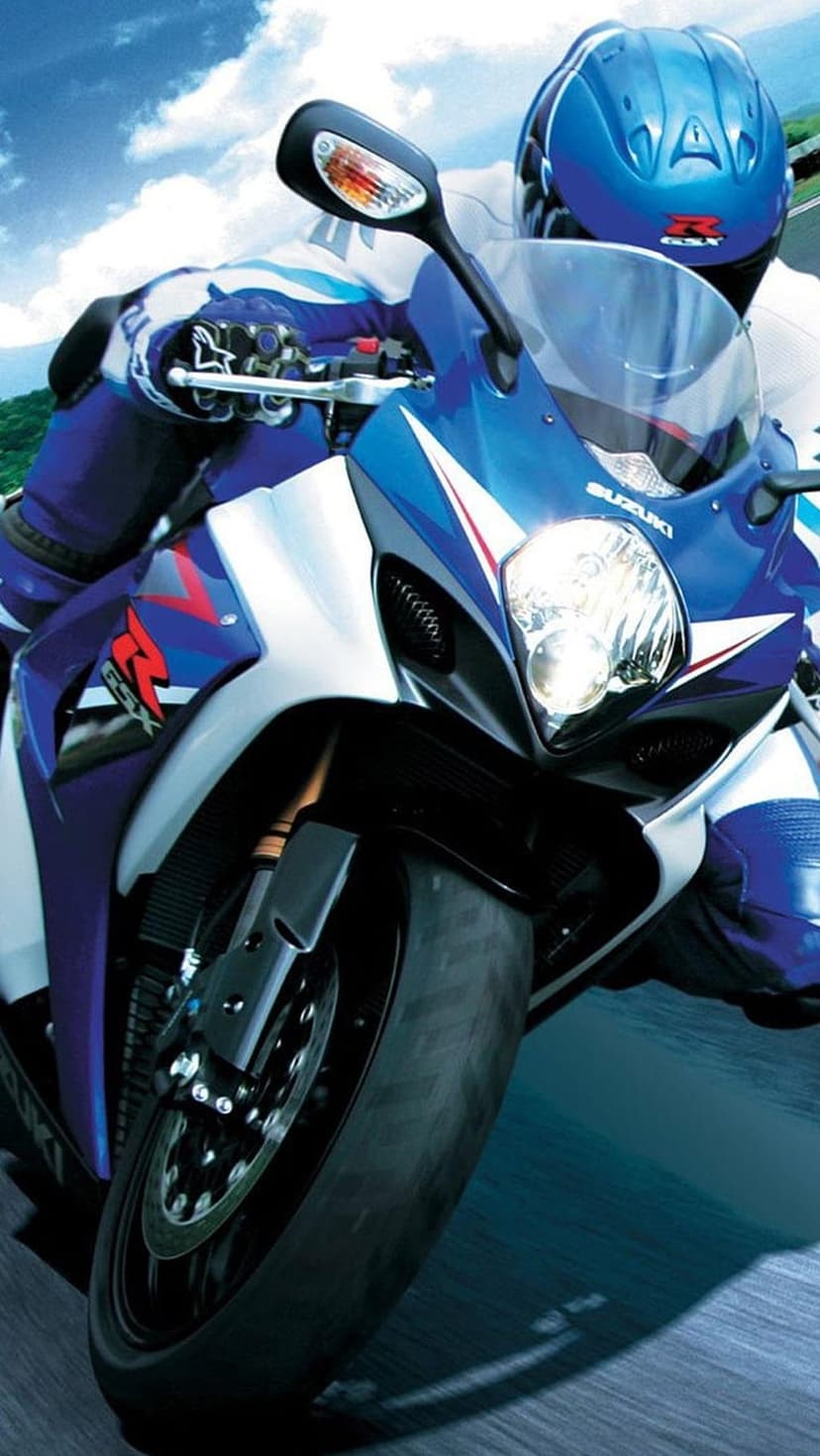 Blue Suzuki GSXR motorcycle rider leans into an asphalt turn on a sunny day with detailed headlights visible.