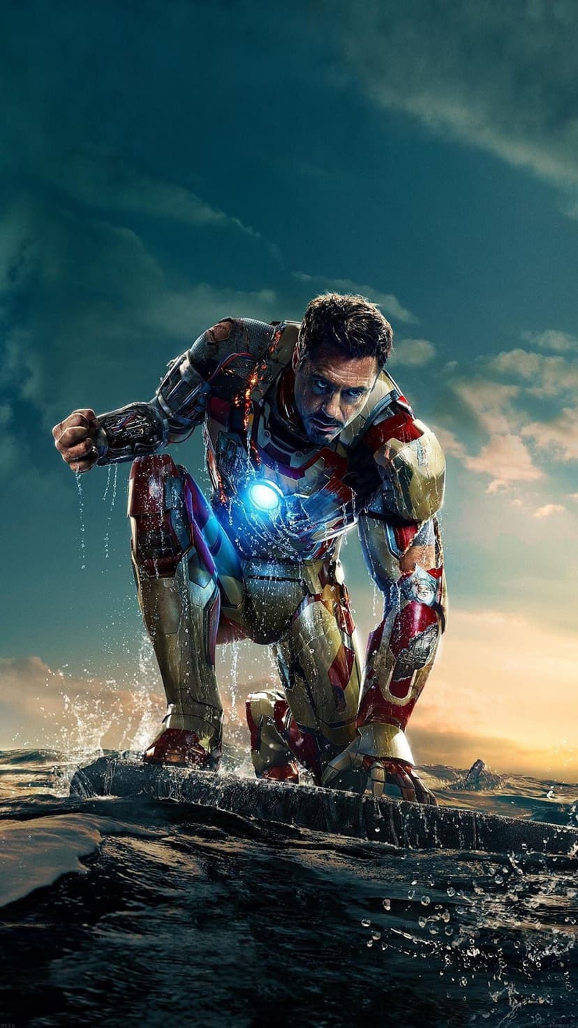 Iron Man in red armor kneels on choppy ocean waves as a bright blue arc reactor glows on his chest at sunset.