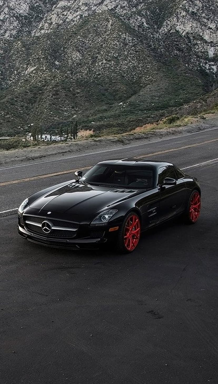 Mercedes SLS AMG with red wheels parked diagonally on a mountain road, providing a high-contrast mobile background.