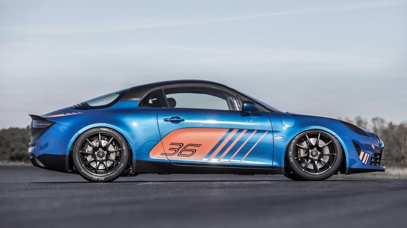 Side profile of a blue Alpine A110 Cup race car with orange graphics and black wheels on a paved track.