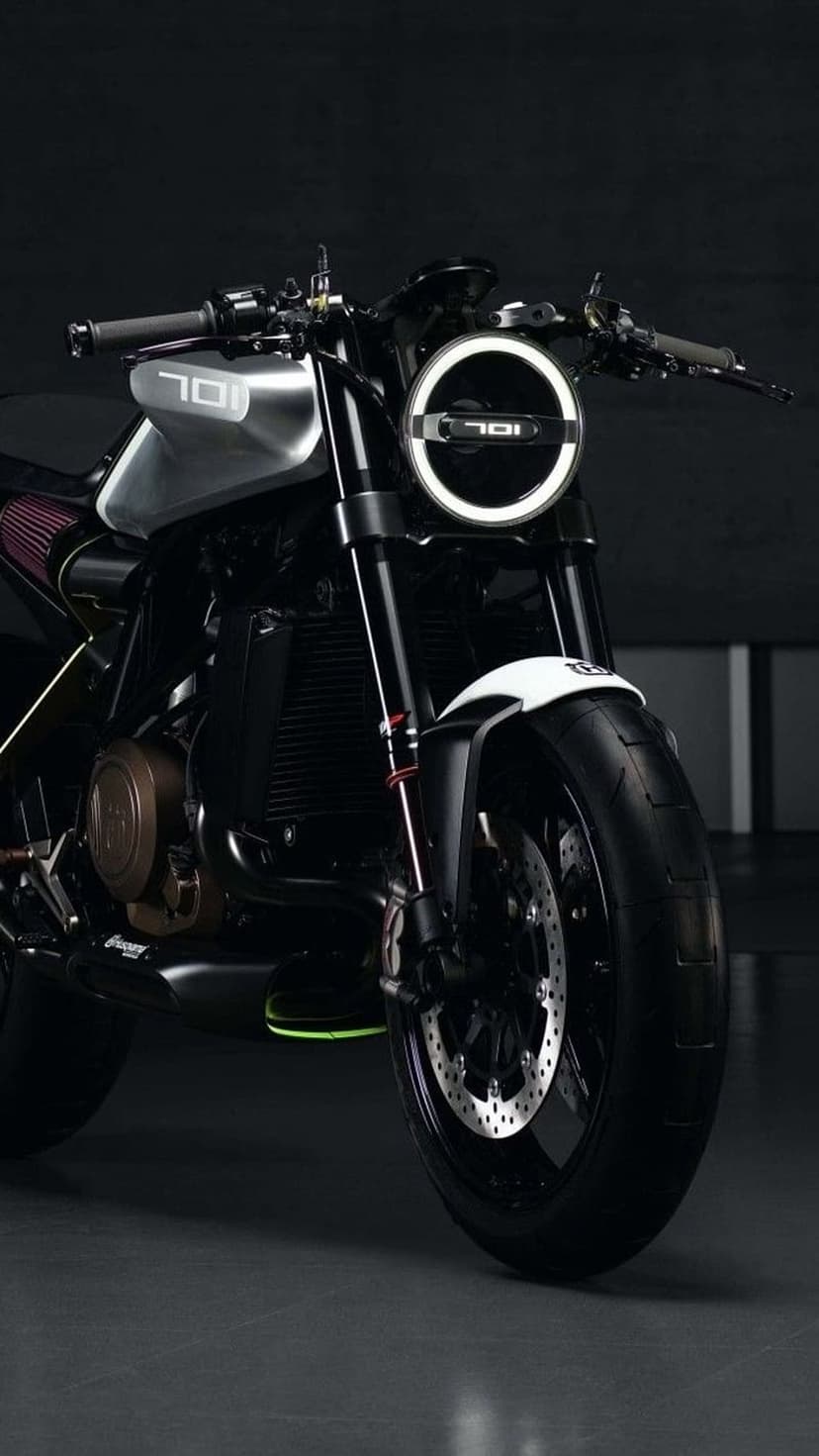 Silver 701 motorcycle featuring a circular LED headlight and knobby tires against a dark, moody background.