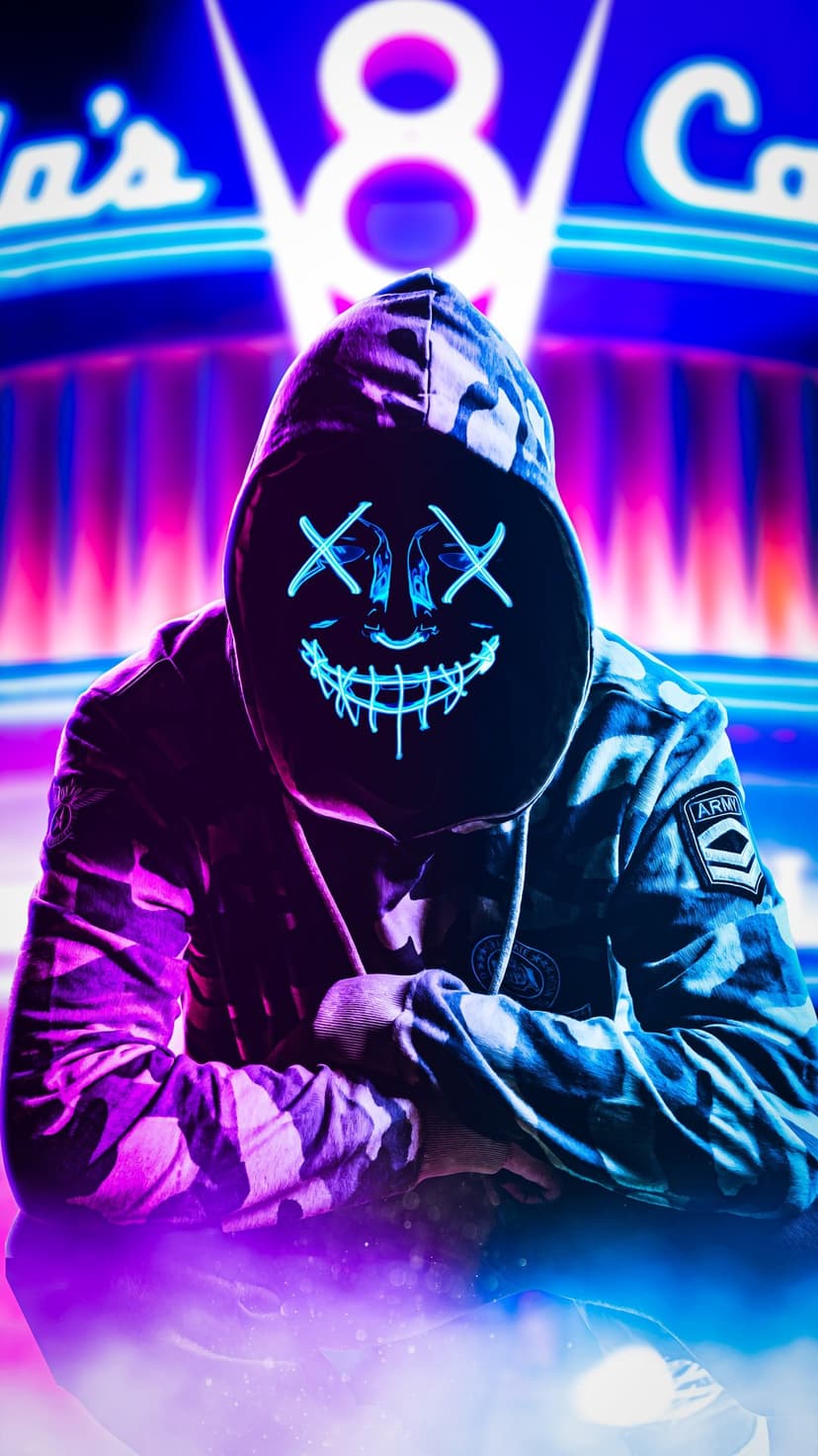 Masked person in a camouflage jacket sits before a blue neon sign with a glowing jagged grin on their face.