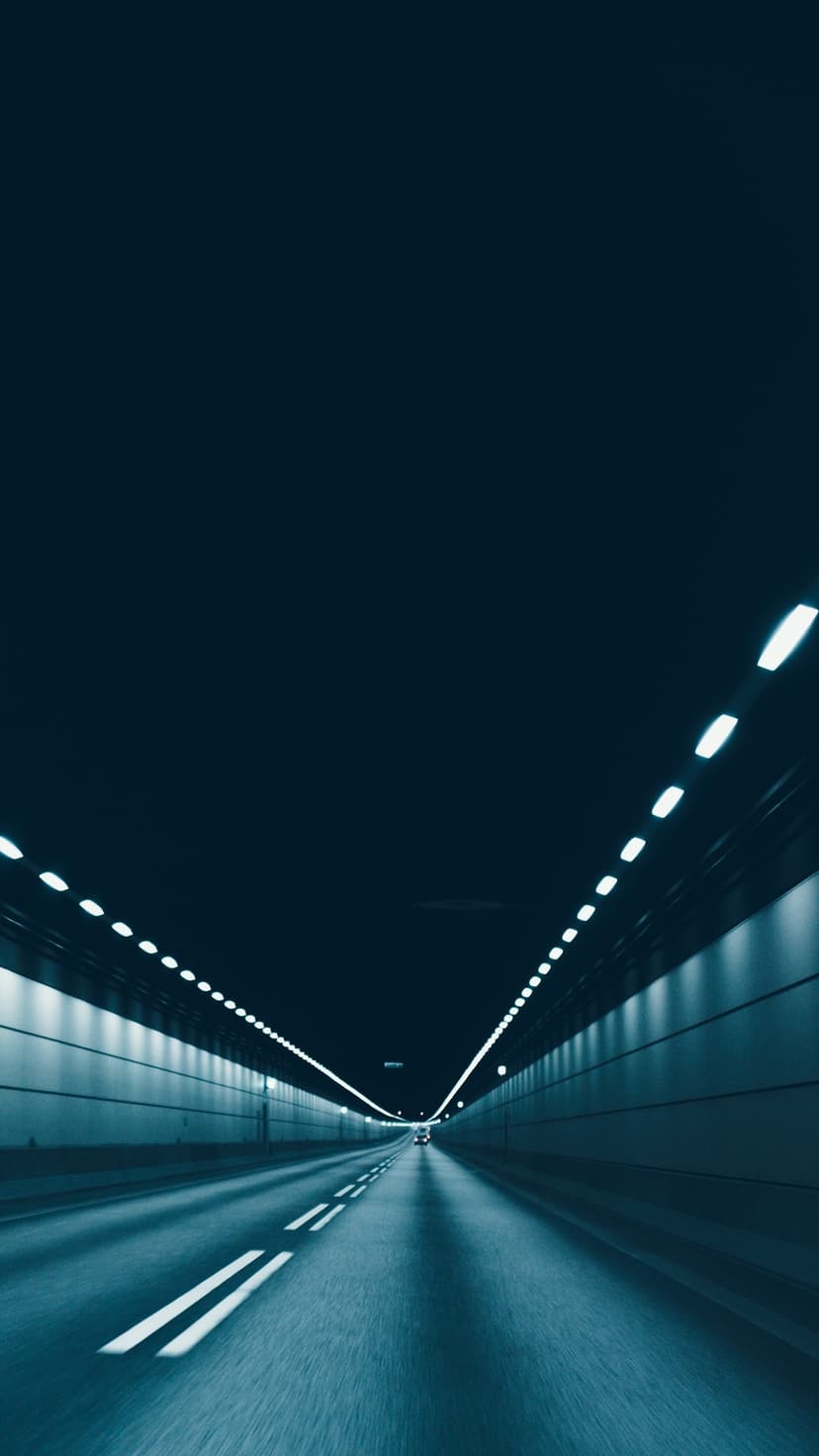 Parallel white lights illuminate a sleek dark underground road in a deep perspective composition for mobile.