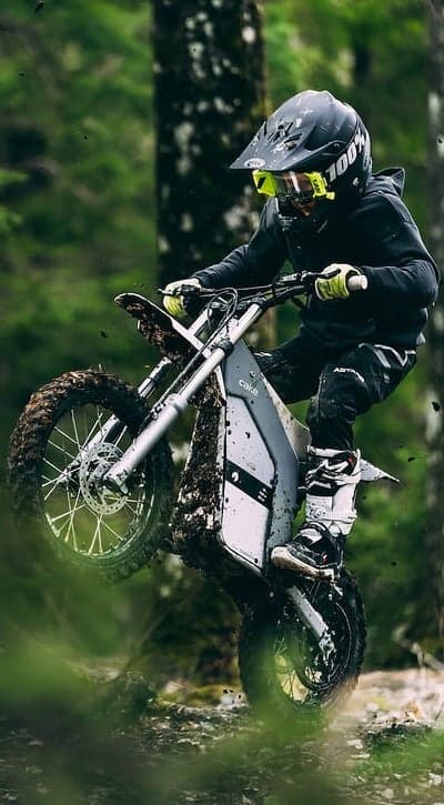 Motocross rider on electric bike in muddy forest trail