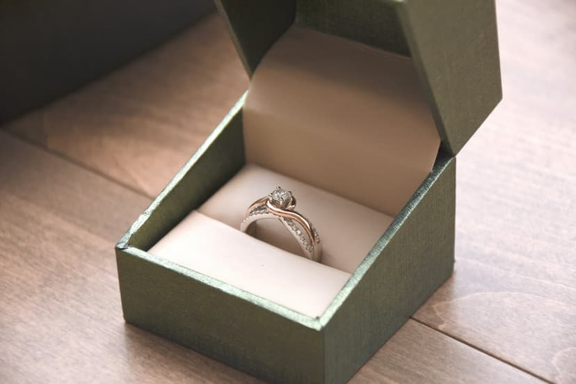 Engagement ring with a central diamond in an open green velvet jewelry box on a rustic wooden surface.