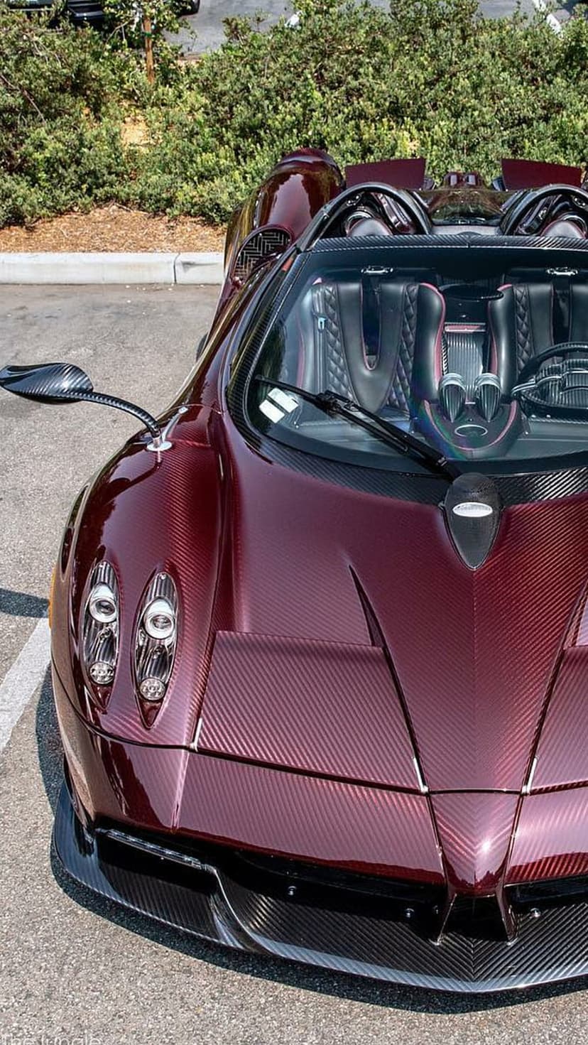 Pagani Huayra Roadster in red carbon fiber featuring aggressive headlights and a quilted leather interior.