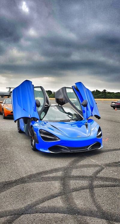 Blue McLaren 720S with dihedral doors open on asphalt