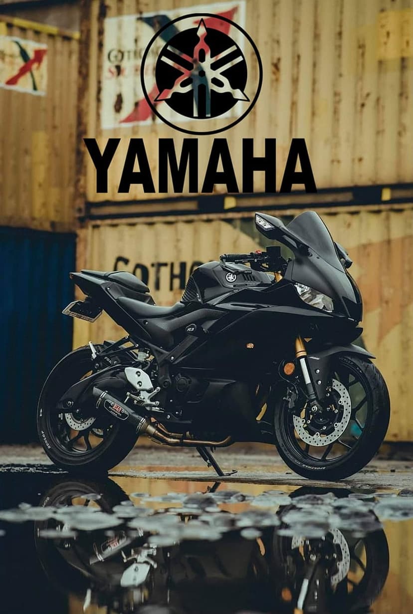 Yamaha sportbike in glossy black sits on wet asphalt mirroring its frame against industrial shipping containers.