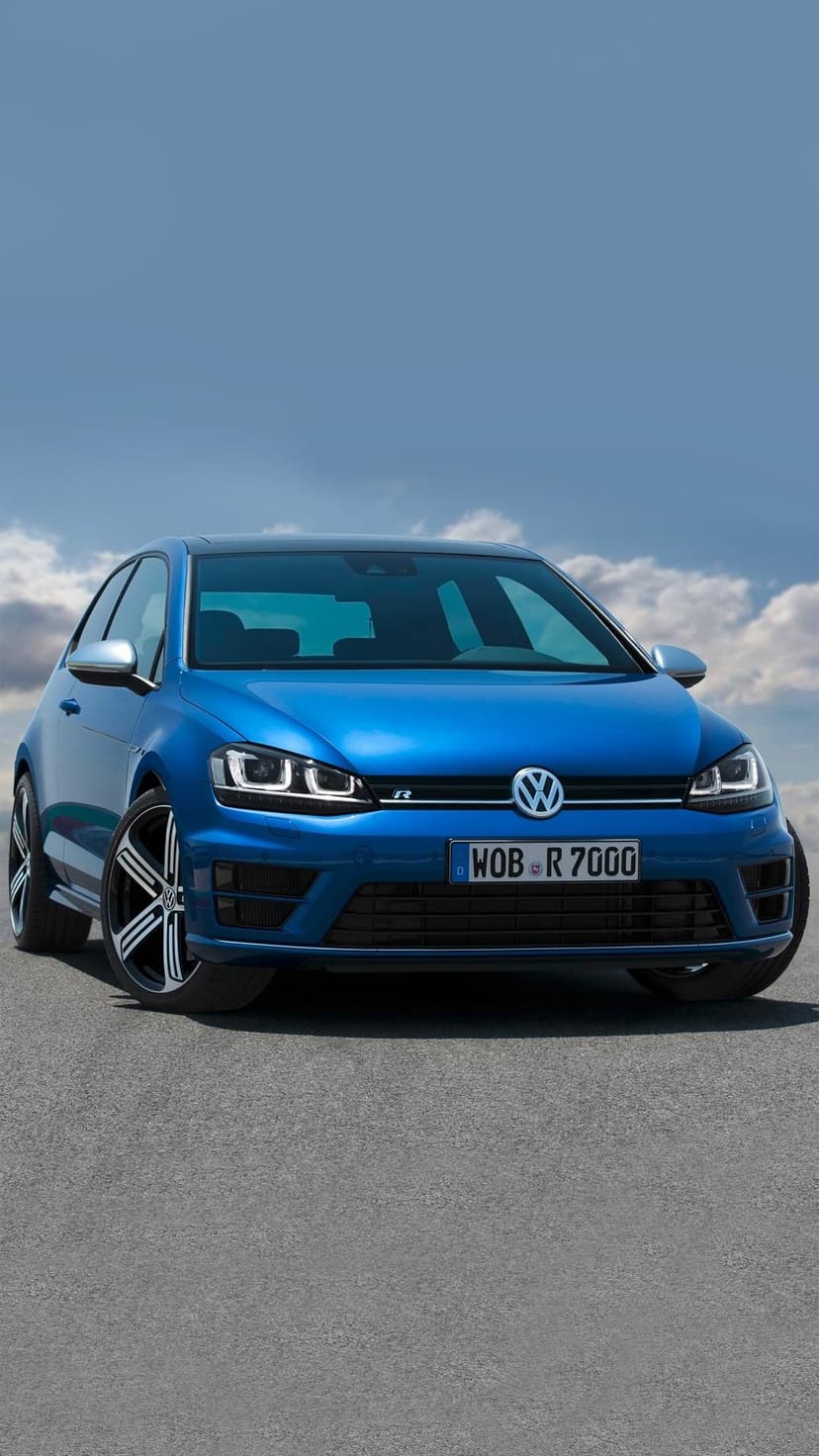 Blue Volkswagen Golf R parked on asphalt under a clear blue sky with white clouds in portrait orientation.