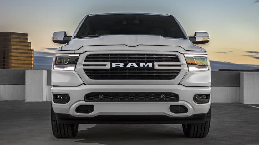 Detailed front view of a white RAM pickup truck with LED headlights on a rooftop under a soft sunset sky.