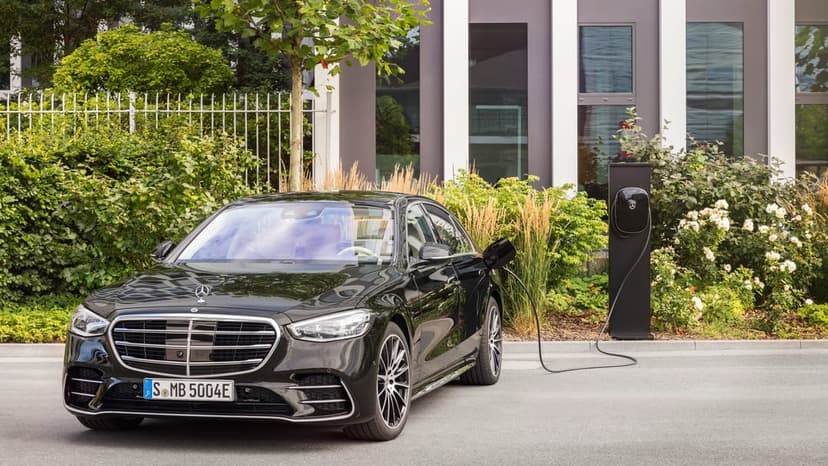 Black Mercedes-Benz S-Class luxury sedan charging at a sleek station beside a modern office building.