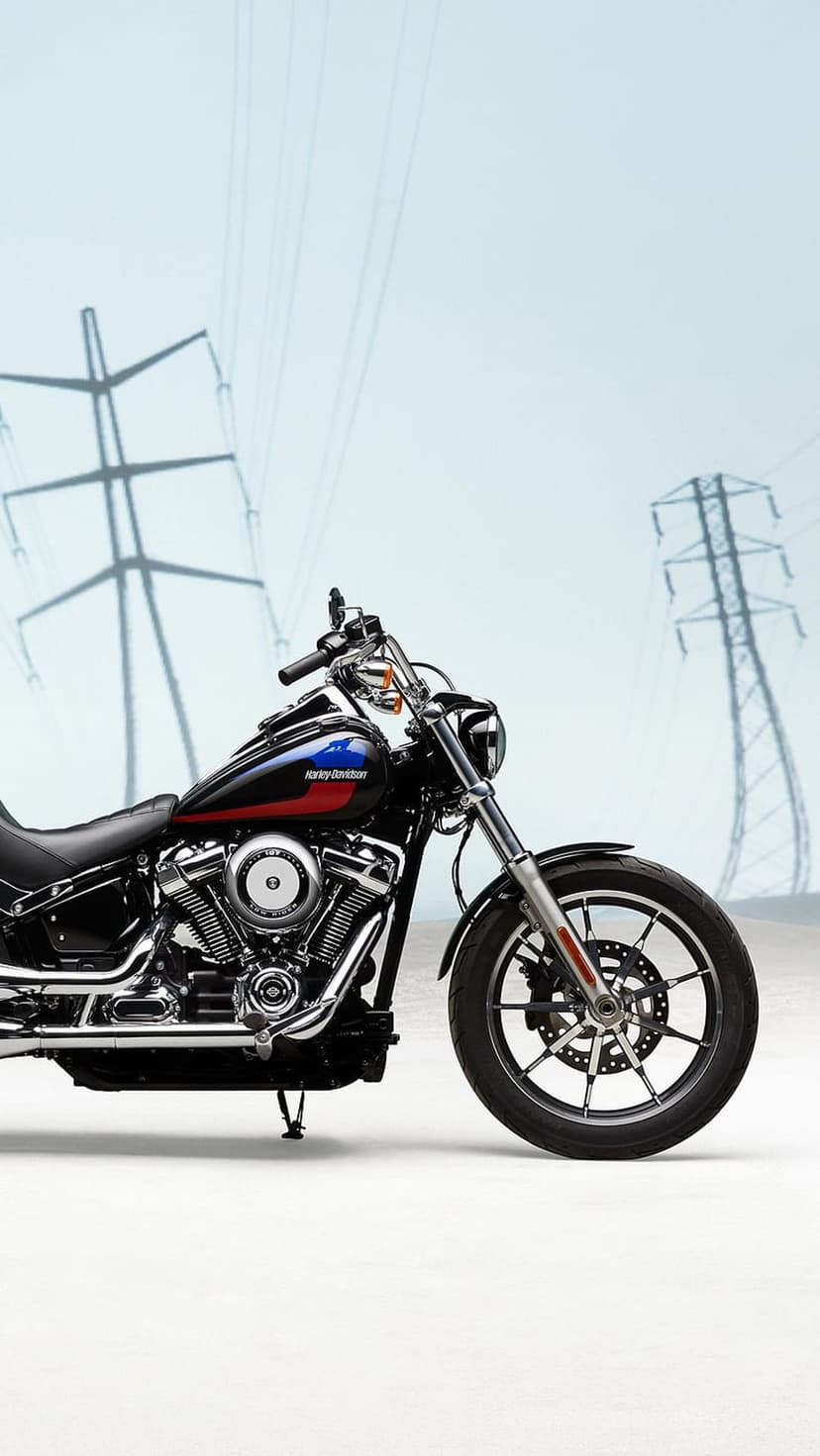 Harley Davidson motorcycle with a black fuel tank parked in front of tall industrial electrical power lines.