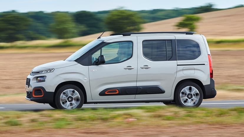 Silver Citroën Berlingo XTR van driving on a road with motion blurred wheels and a rural background.