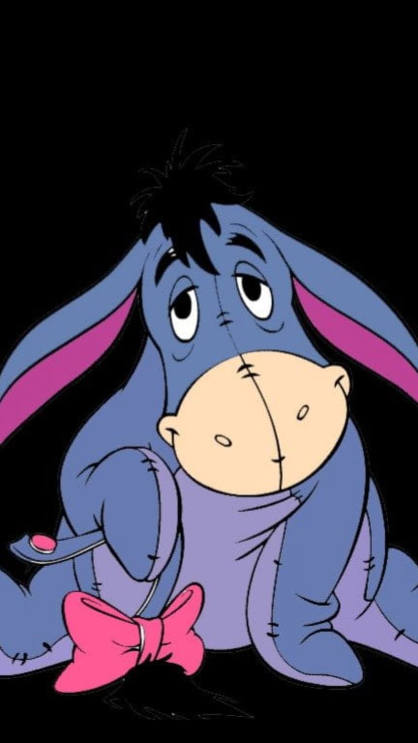 Eeyore the blue donkey sits with sad eyes and a pink bow on his tail against a solid black background.
