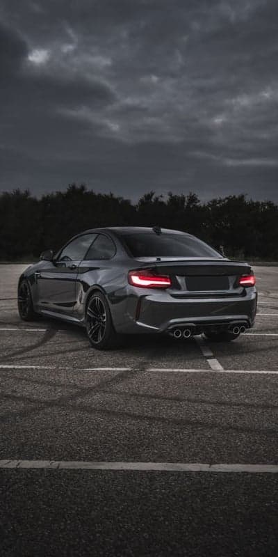 Dark BMW M2 Coupe with Smoking Tires on Asphalt