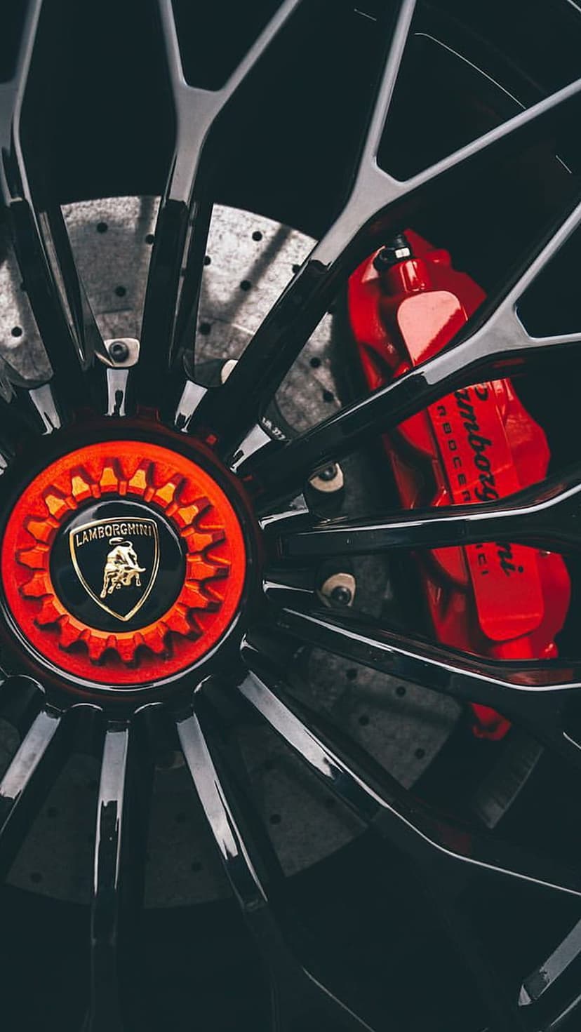 Lamborghini wheel with red calipers and gold bull crest showcasing intricate metal textures and black spokes.