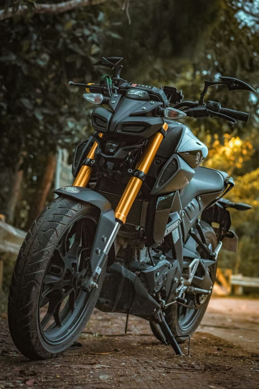 Yamaha MT motorcycle front view featuring gold suspension forks and LED headlights against a blurred forest.