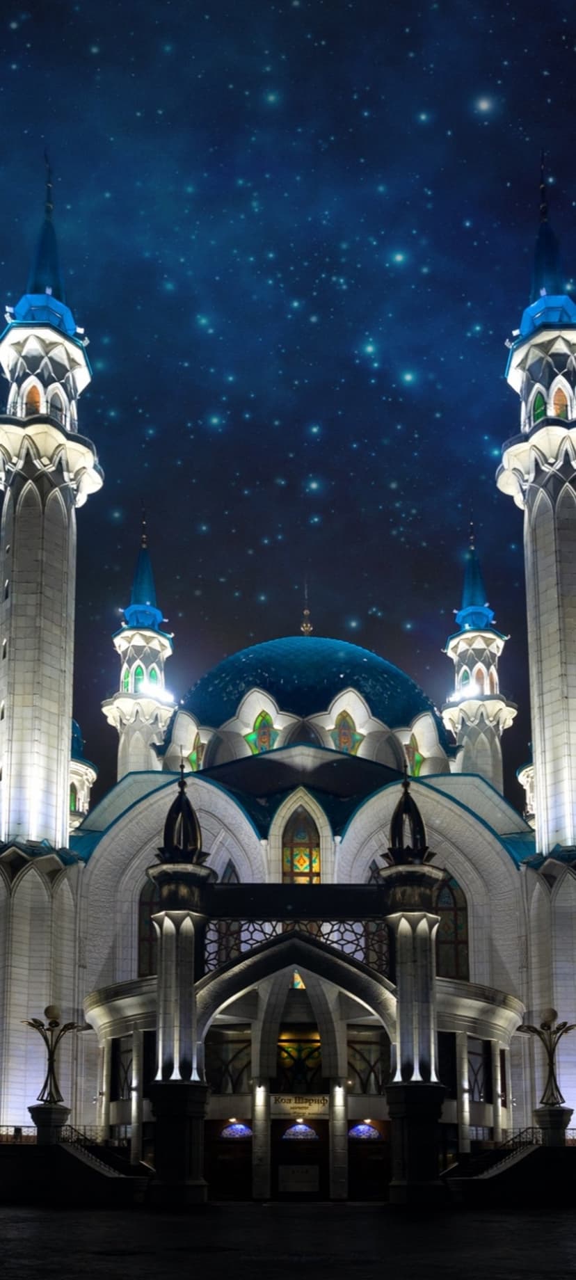 Kul Sharif Mosque features white minarets and blue domes illuminated against a twinkling night sky in Kazan.