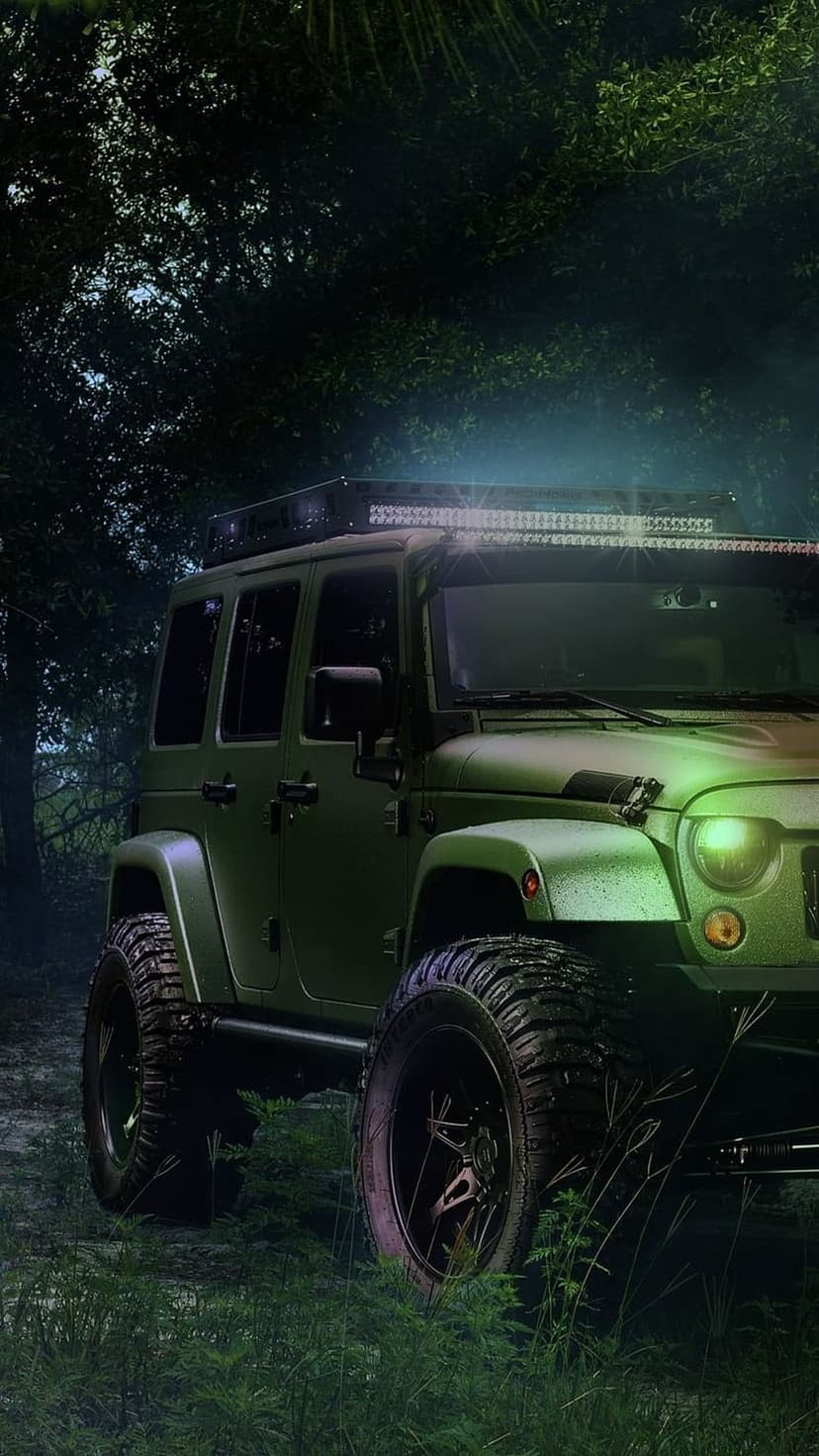 Matte green Jeep Wrangler with an illuminated LED light bar parked in a dark, misty forest during the night.