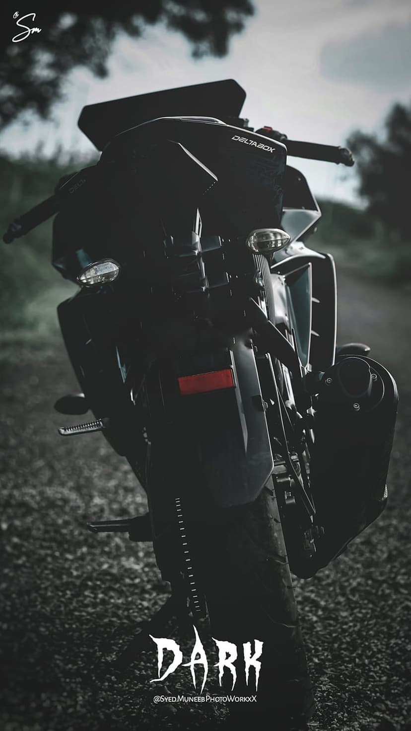 Matte black sportbike tail section with visible exhaust and stylized text under low atmospheric night lighting.