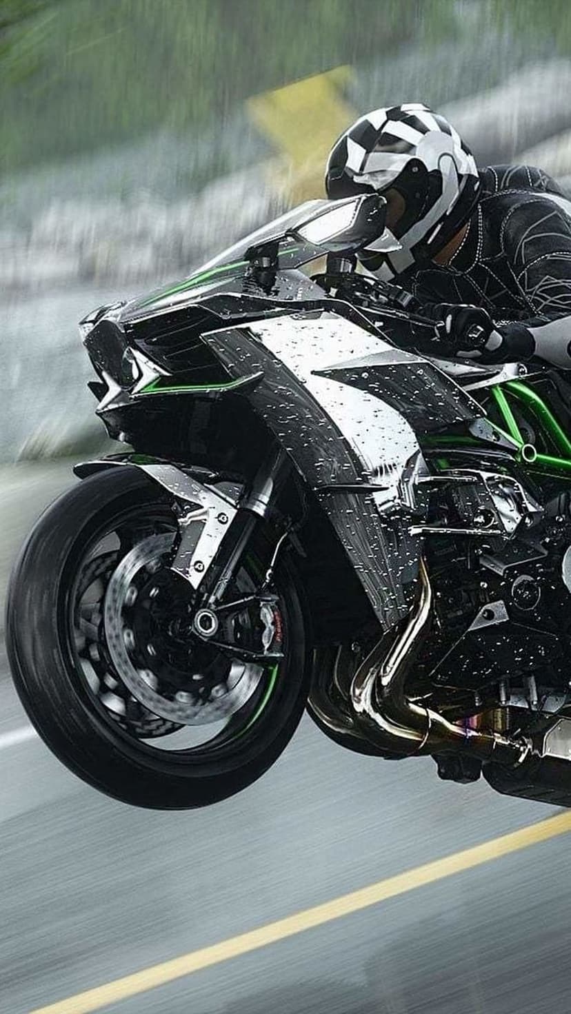 Kawasaki Ninja H2R sportbike with water droplets on its fairing speeds through rain on a blurred asphalt road.