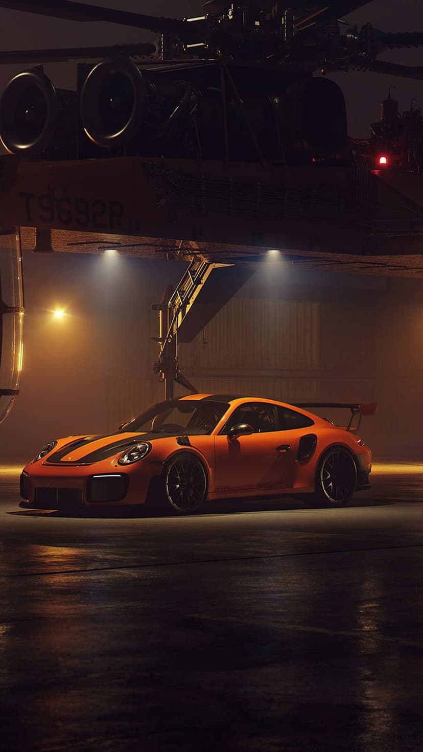 Orange Porsche 911 GT2 RS with black stripes parked under a helicopter inside a hangar with atmospheric lighting.