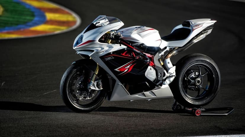 MV Agusta F4 superbike parked on a dark asphalt race track with a colorful curb and dramatic sunlight.
