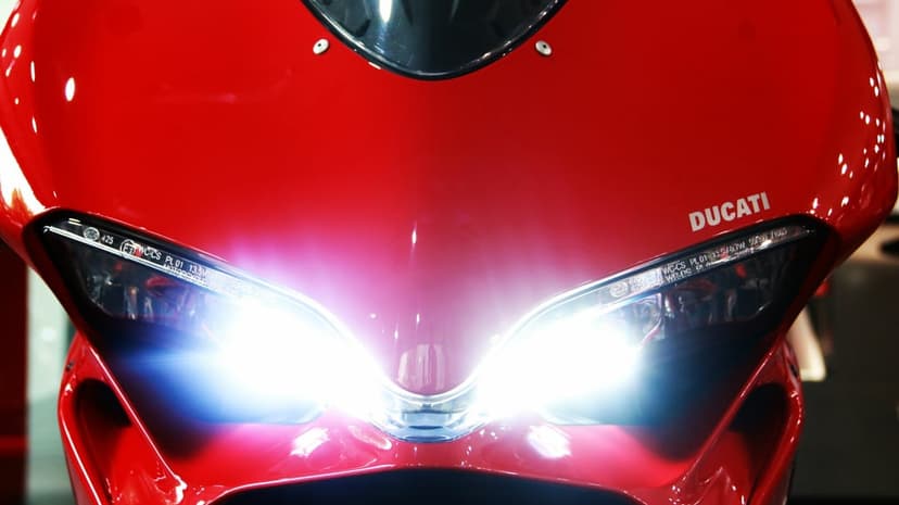 Red Ducati motorcycle front fairing with bright glowing white LED headlights and glossy scarlet paint.