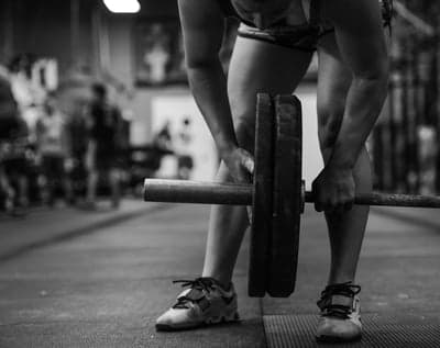 Person prepares to lift heavy barbell in gym
