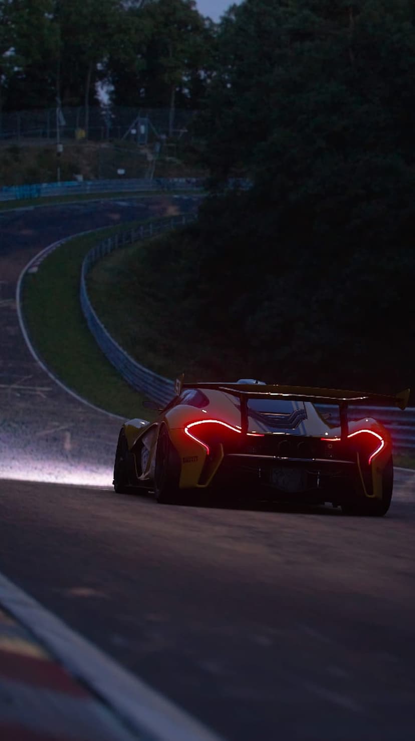 McLaren P1 supercar with glowing red taillights speeds through a dark racing circuit at dusk under a moody sky.