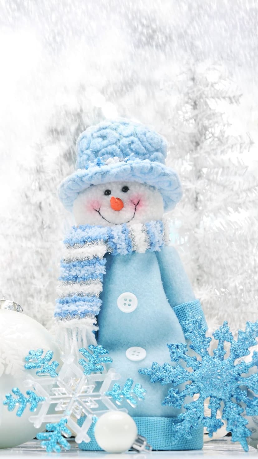 Blue snowman figurine wearing a hat and scarf surrounded by white ornaments and glittering snowflakes in winter.