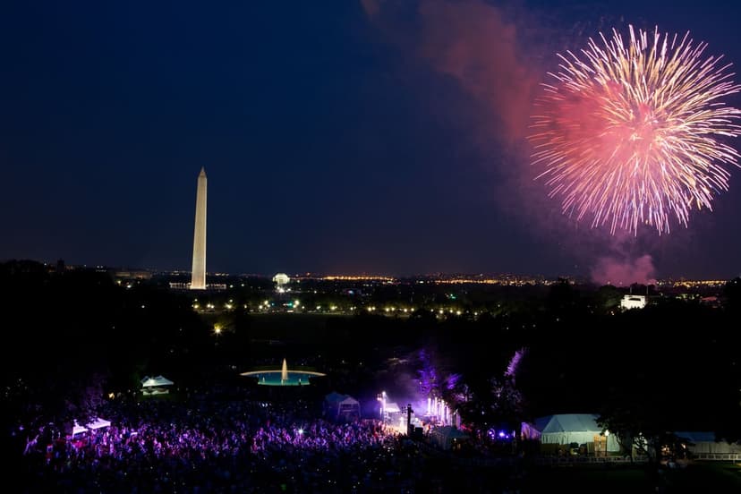 Washington Monument and U.S. Capitol under a night sky filled with colorful fireworks above a crowded city mall.