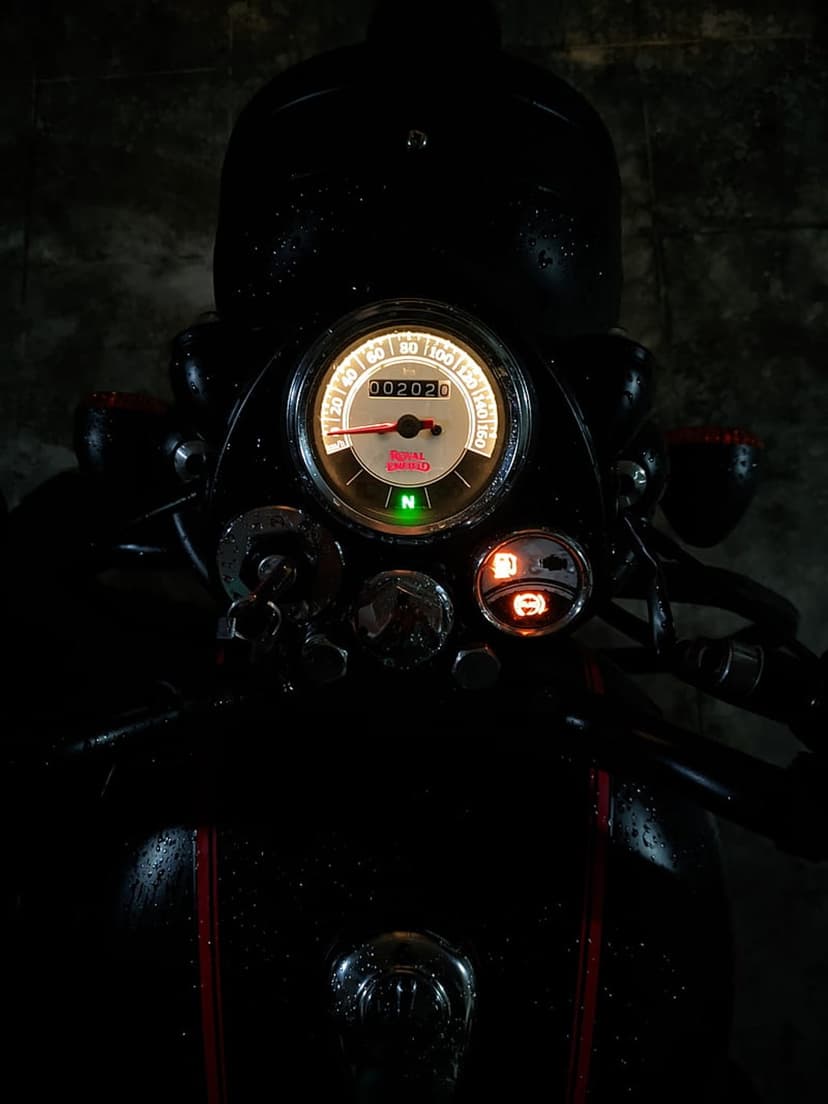 Motorcycle speedometer with glowing amber numbers and chrome housing captured in a low-light night environment.