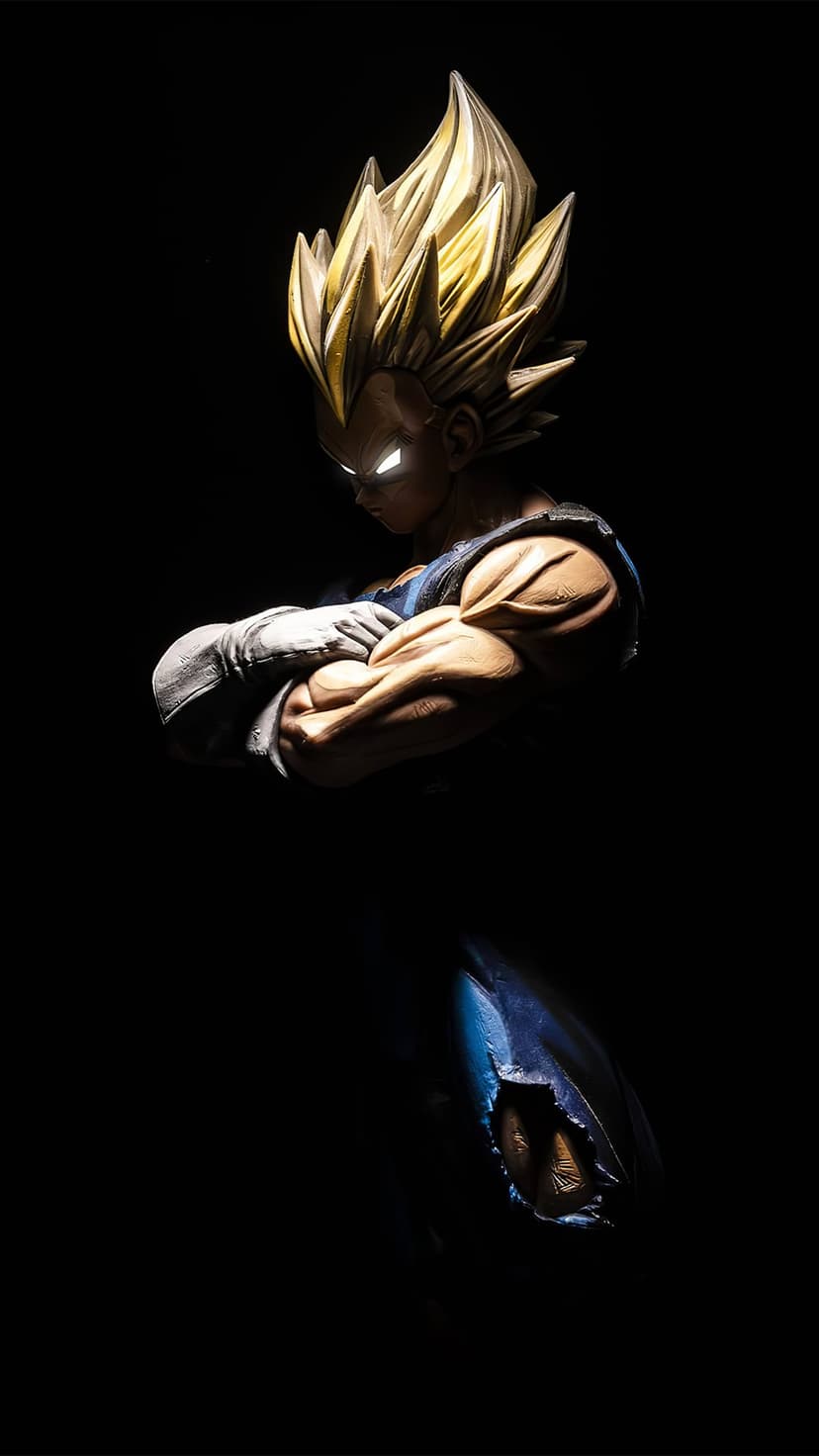 Vegeta figurine with golden spiky hair and glowing white eyes stands with arms crossed against a black background.