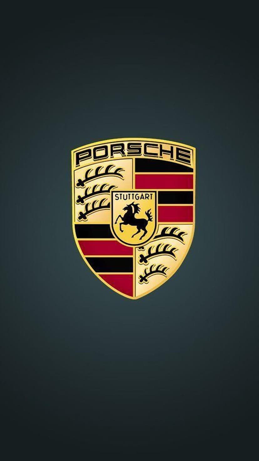 Porsche shield emblem with a black horse on a yellow background and red stripes, set on a dark textured surface.