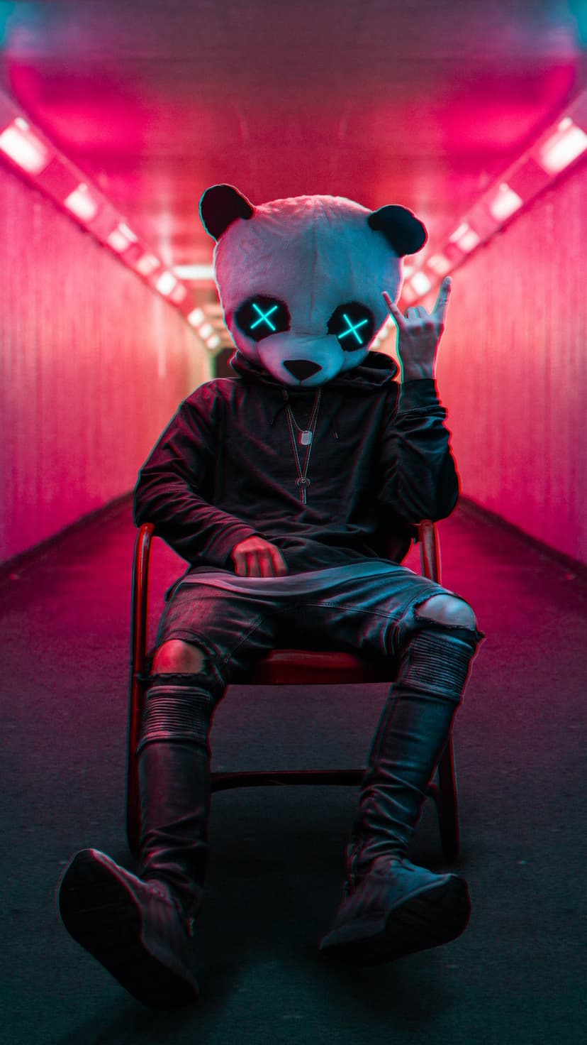 Person in a panda mask with glowing blue eyes sits in a red chair within a pink and blue neon tunnel.