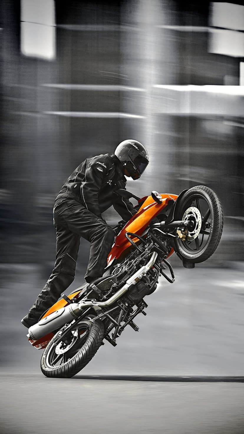 Motorcyclist in black gear performs a wheelie on an orange sportbike against a blurred background of motion lines.