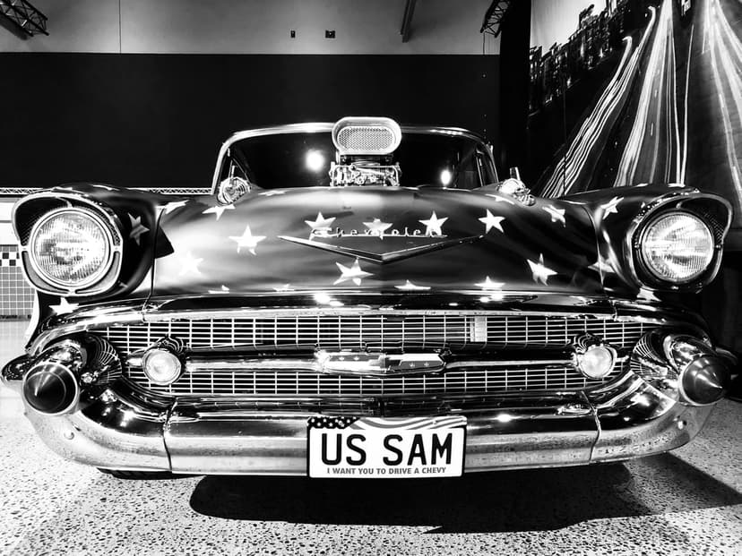 Vintage Chevrolet car with a stars and stripes flag pattern on the hood and chrome grille in monochrome.